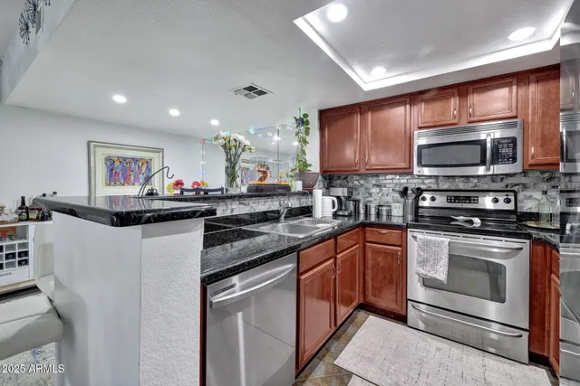 a kitchen with stainless steel appliances granite countertop a stove microwave and sink