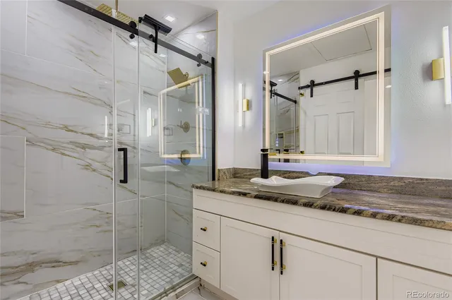 a bathroom with a granite countertop sink mirror and shower