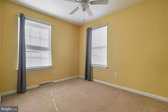 an empty room with a window and a ceiling fan