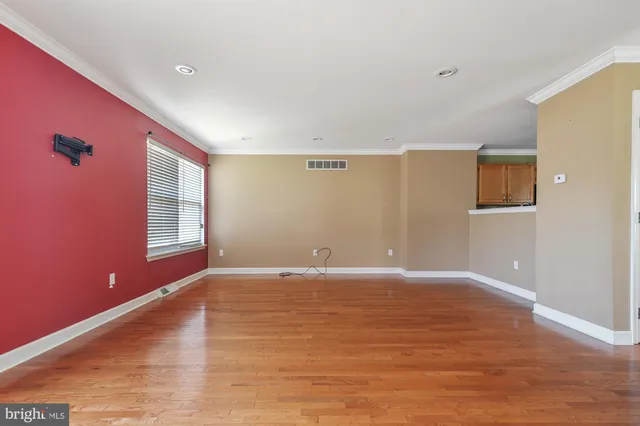a view of an empty room with window and wooden floor