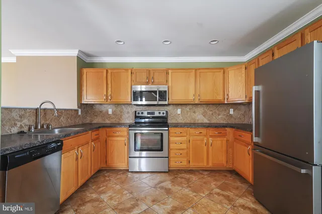 a kitchen with stainless steel appliances granite countertop a refrigerator sink stove microwave and cabinets