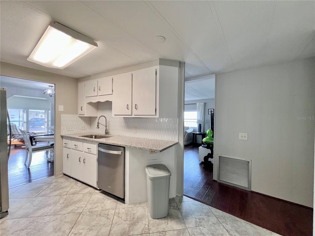 1100 South Belcher Road, Unit 772 Largo, FL 33771 - Photo 22 of 84 a kitchen with a sink dishwasher a stove and white cabinets with wooden floor