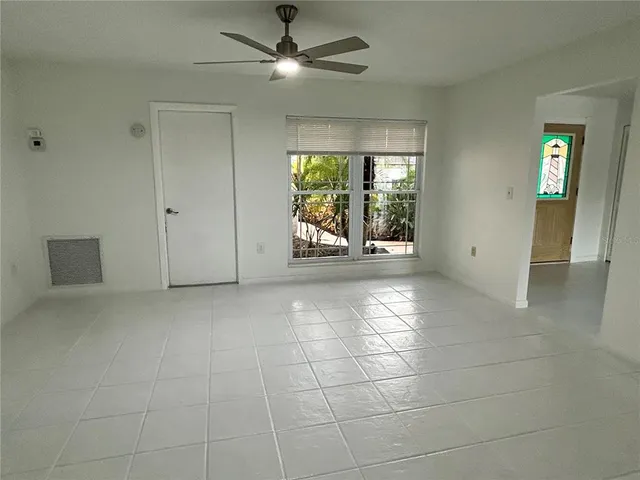 a view of an empty room with window and chandelier fan