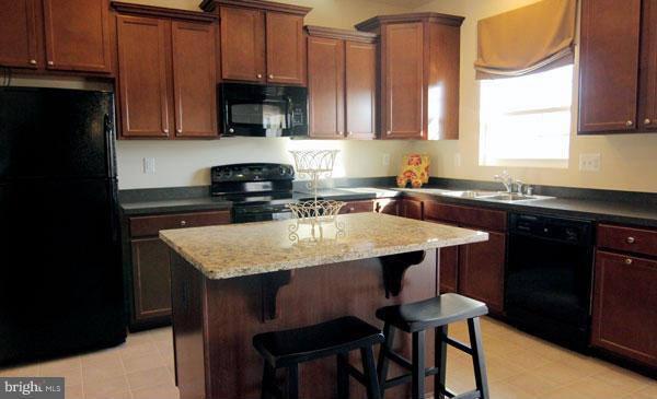 7705 Sentry Terrace Severn, MD 21144 - Photo 6 of 18 a kitchen with a sink a microwave a stove and refrigerator