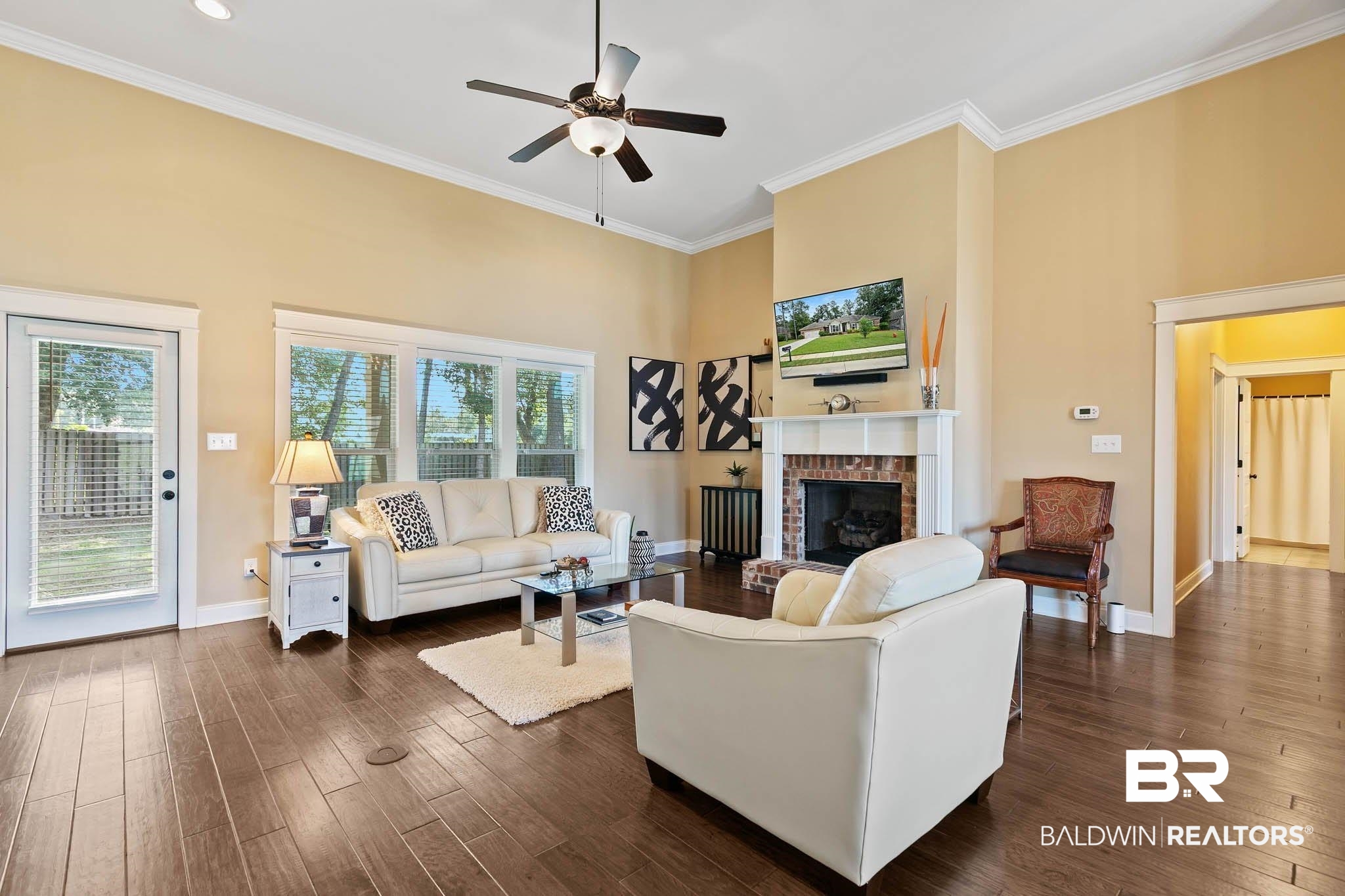 19740 Bunker Loop Fairhope, AL 36532 - Photo 5 of 33 Living area featuring a towering ceiling, crown molding, a brick fireplace, dark wood finished floors, and ceiling fan