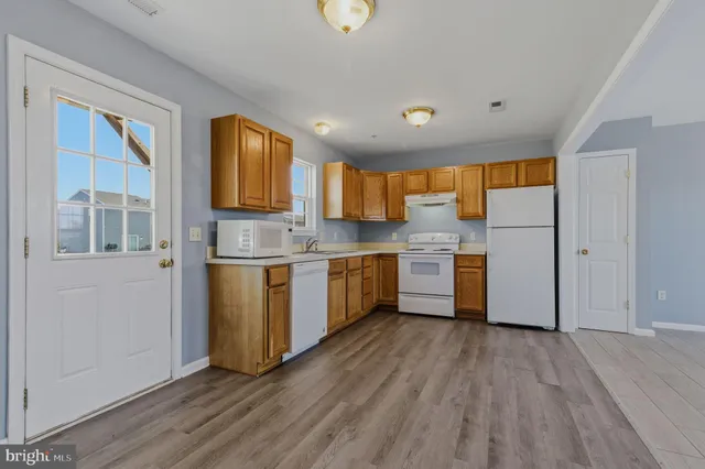 a kitchen with stainless steel appliances granite countertop a stove a sink and a refrigerator with wooden floors