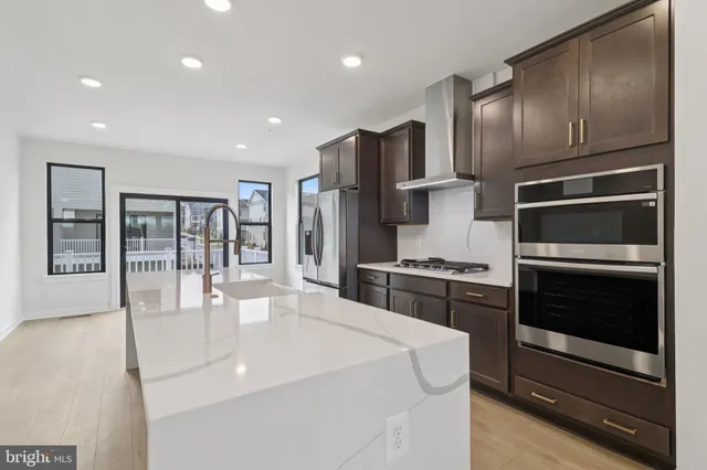 a kitchen with stainless steel appliances kitchen island granite countertop a stove a refrigerator and a sink with wooden cabinets