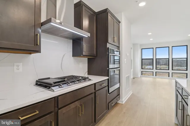 a kitchen with stainless steel appliances a stove a sink and a refrigerator with wooden floor