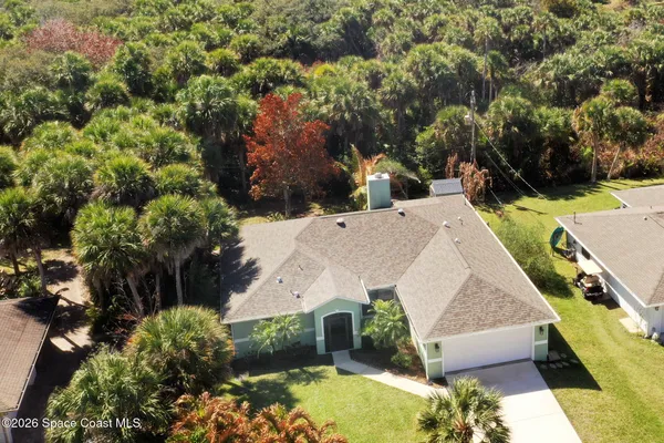 an aerial view of a house with swimming pool and large trees