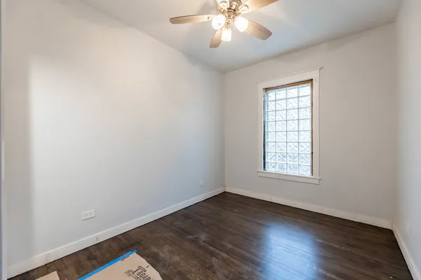 an empty room with wooden floor chandelier fan and windows
