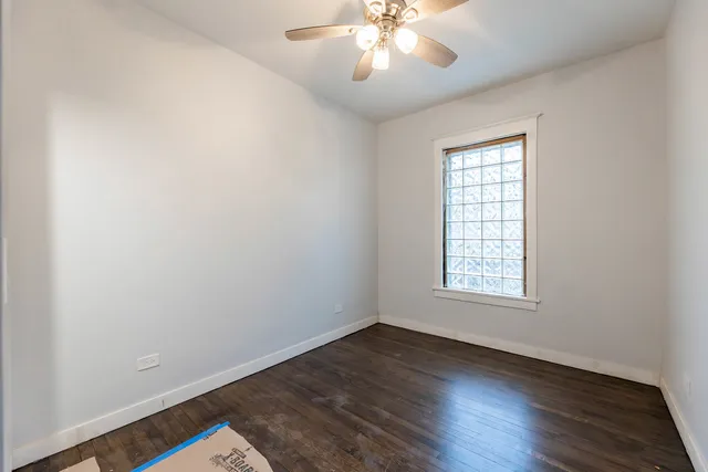 an empty room with wooden floor chandelier fan and windows