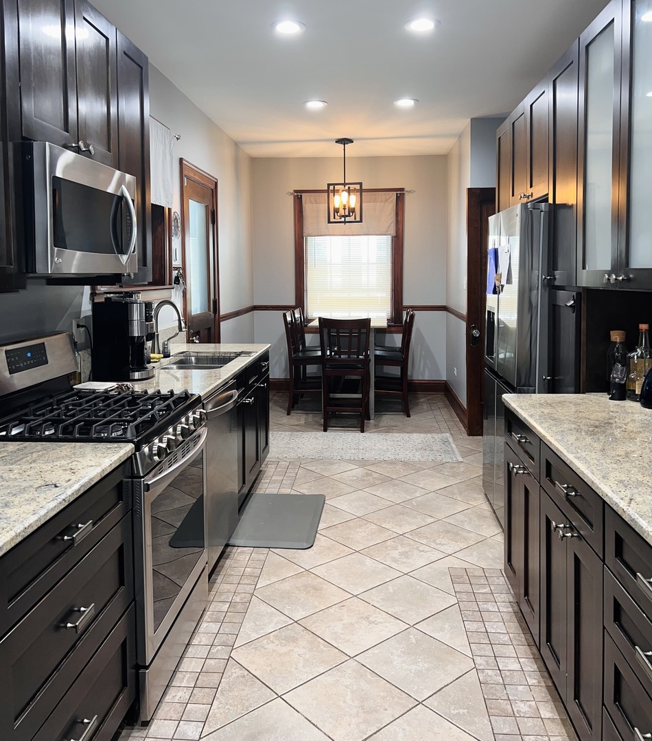 6849 Riverside Drive Berwyn, IL 60402 - Photo 10 of 33 a kitchen with stainless steel appliances granite countertop a stove a sink and a microwave