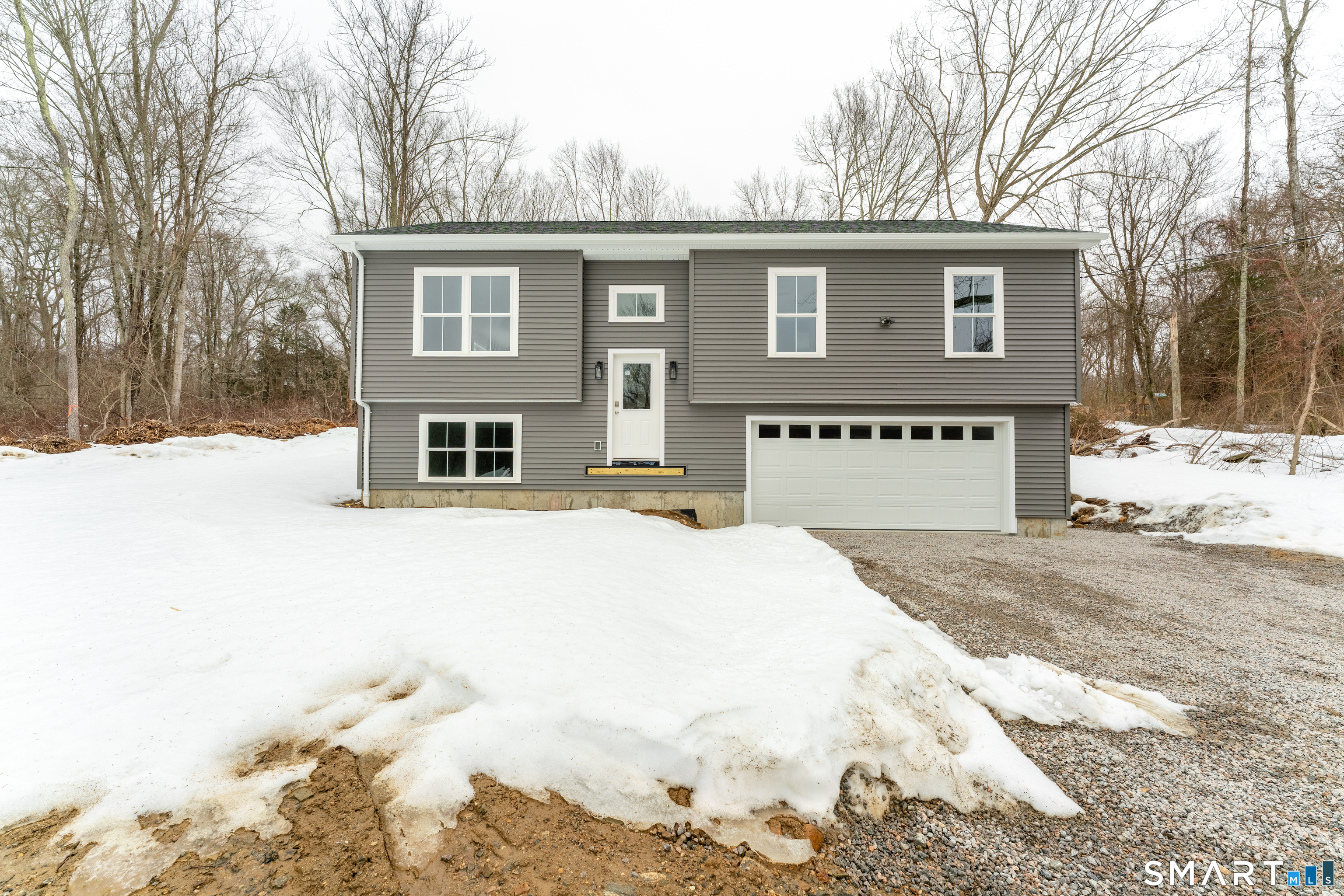 a front view of a house with a yard covered in snow