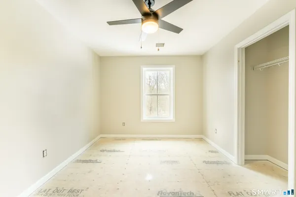 an empty room with a window and a chandelier fan