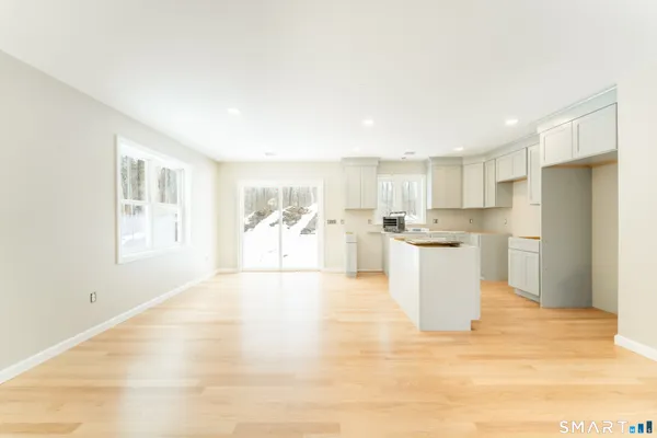 a view of a kitchen with wooden floor and white cabinets