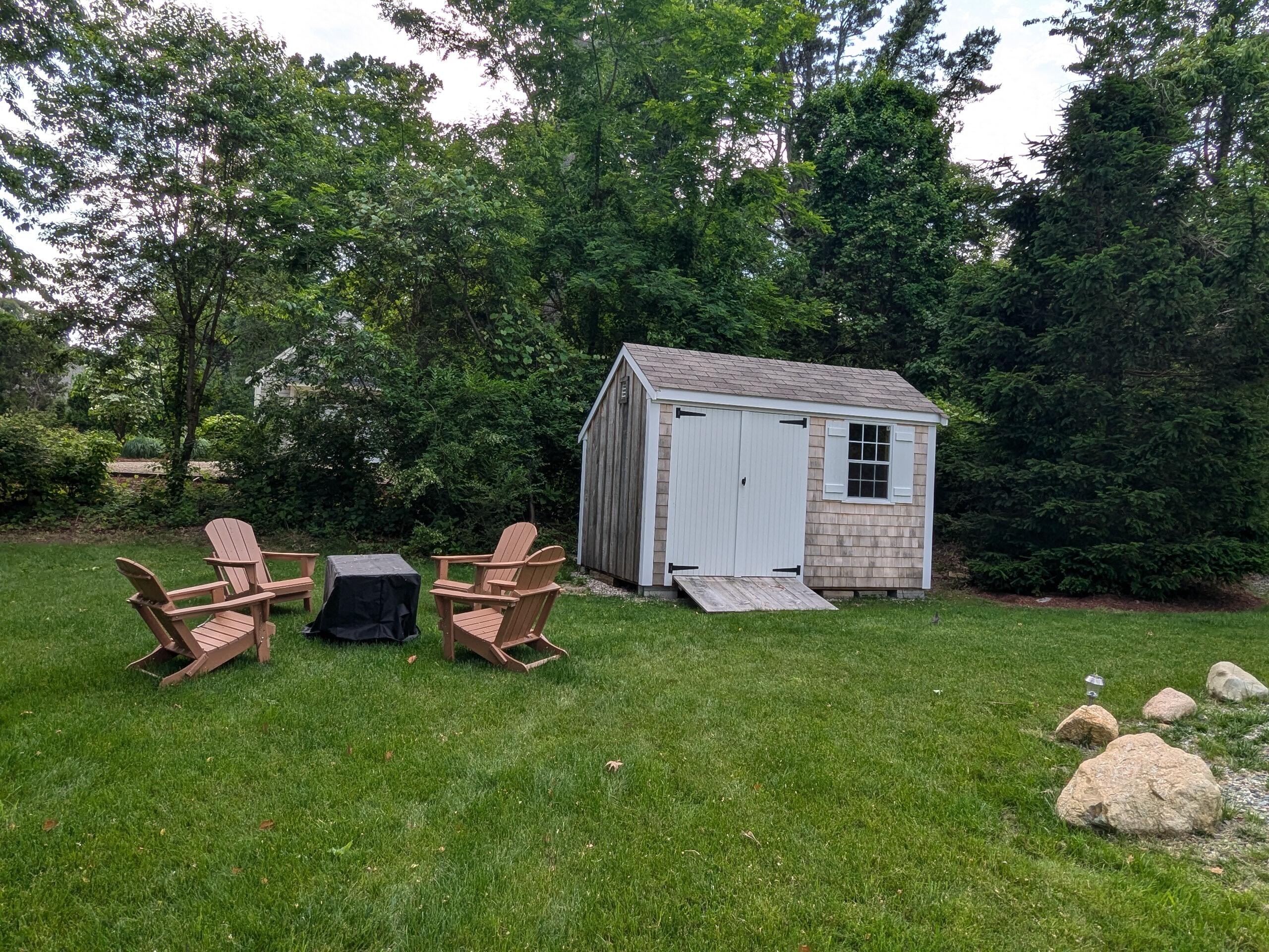 29 Pilgrim Road Dennis, MA 02638 - Photo 40 of 54 a backyard of a house with table and chairs a barbeque with a fire pit