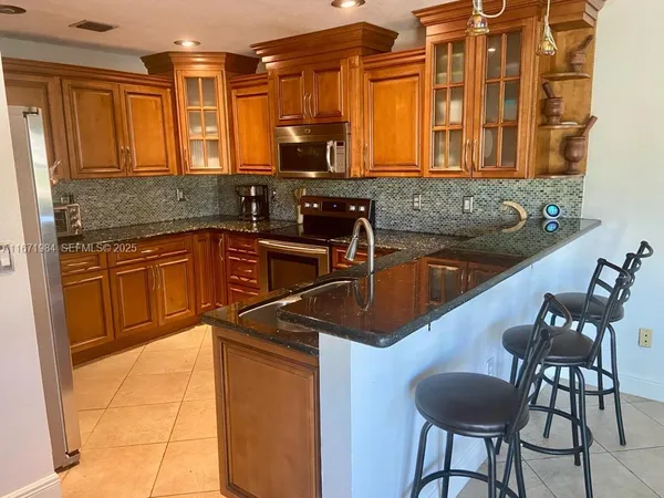 a kitchen with stainless steel appliances granite countertop a sink and a refrigerator