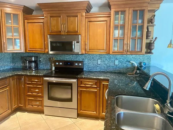 a kitchen with granite countertop a stove sink and cabinets
