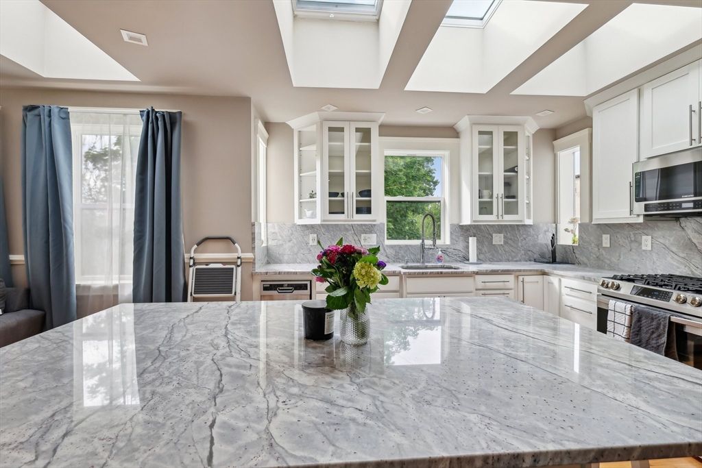51 Hamilton Street, Unit 3 Boston, MA 02125 - Photo 11 of 21 a kitchen with stainless steel appliances kitchen island granite countertop a refrigerator a stove and a sink with granite countertops