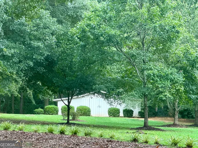 a view of a white house in a big yard with large trees