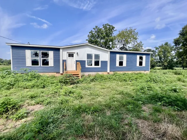 a front view of house with yard and trees in the background
