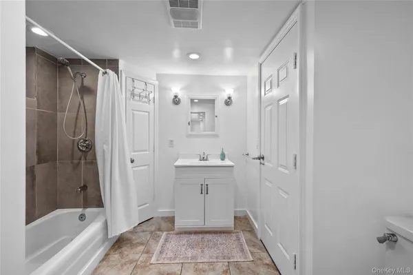 a bathroom with a bathtub shower sink and mirror