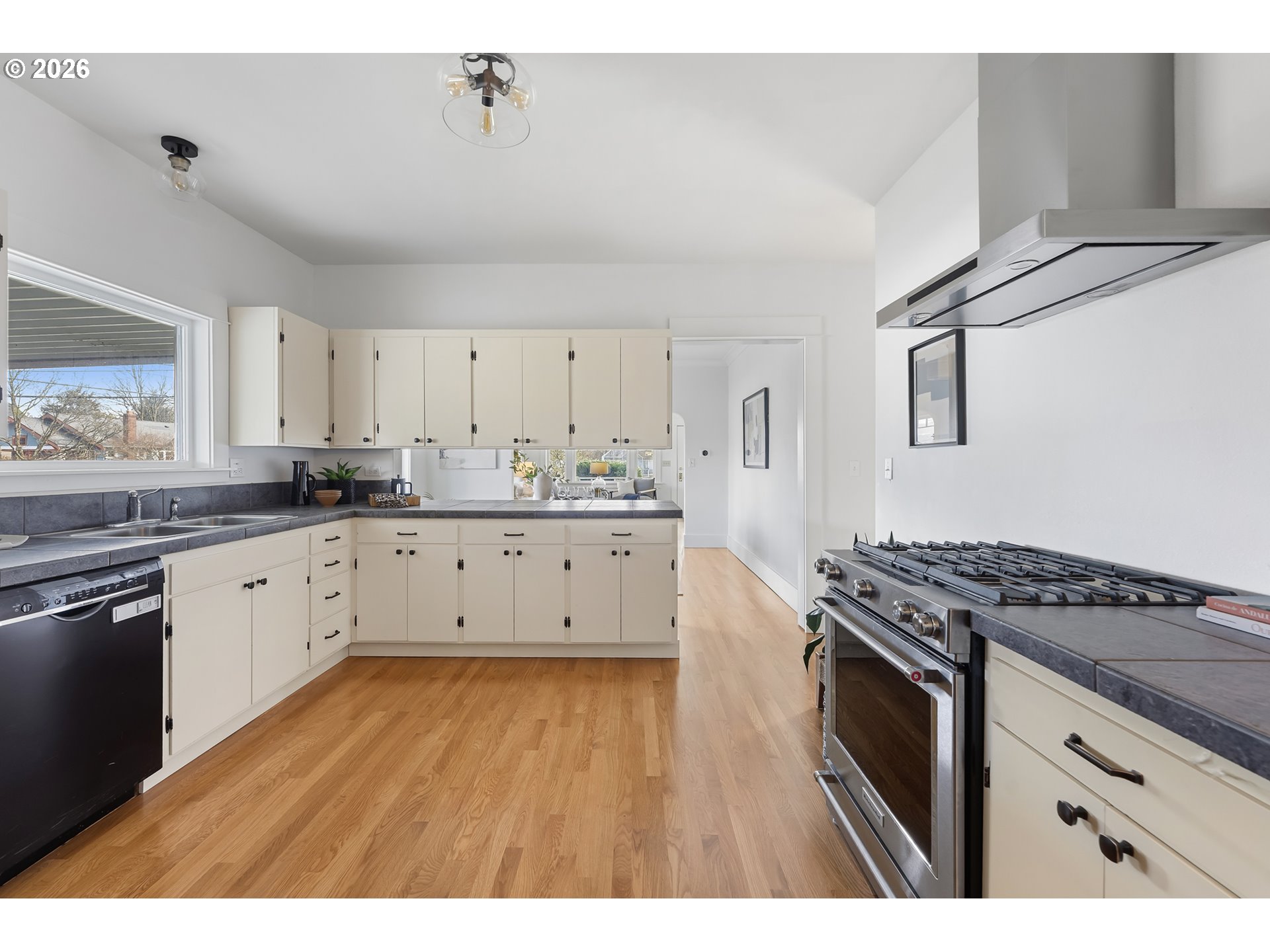 2845 Northeast 53rd Avenue Portland, OR 97213 - Photo 10 of 29 a kitchen with stainless steel appliances granite countertop a stove a sink dishwasher and white cabinets with wooden floor