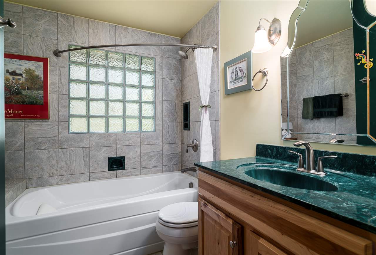 3310 East Whitaker Road Byron, IL 61010 - Photo 12 of 25 a bathroom with a granite countertop sink a toilet a mirror and bathtub