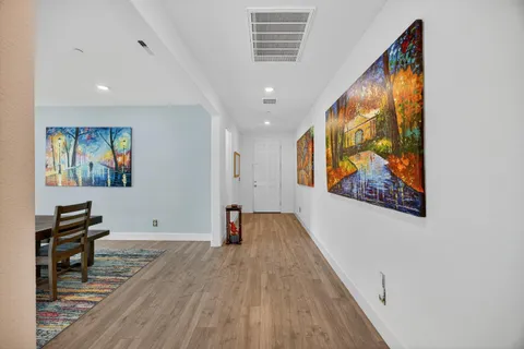 a view of a hallway with wooden floor and furniture