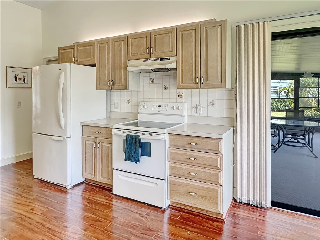 5408 Eagle Drive Fort Pierce, FL 34951 - Photo 3 of 35 a kitchen with a refrigerator stove and white cabinets with wooden floor