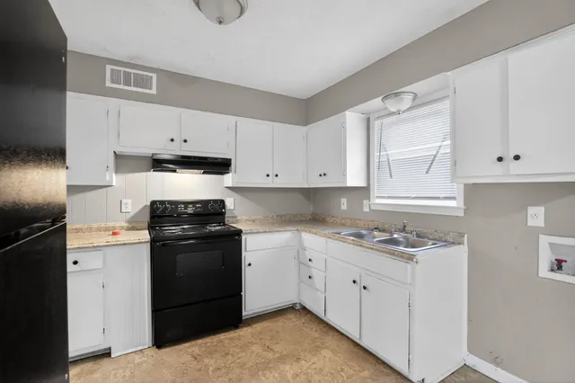 a kitchen with white cabinets and appliances