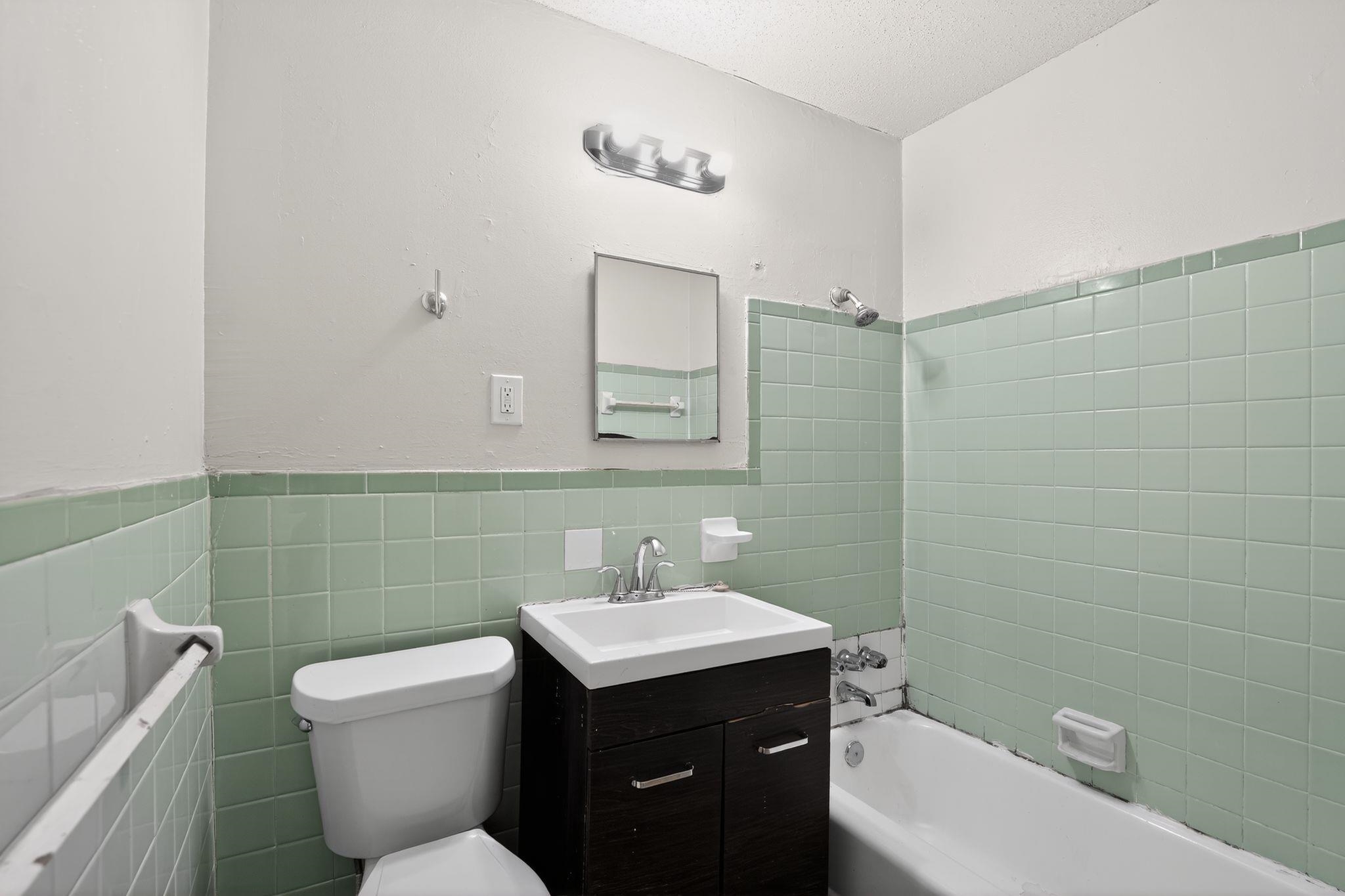 4314 Ford Road Memphis, TN 38109 - Photo 26 of 31 Bathroom featuring tile walls, a wainscoted wall, vanity, and shower / bathtub combination