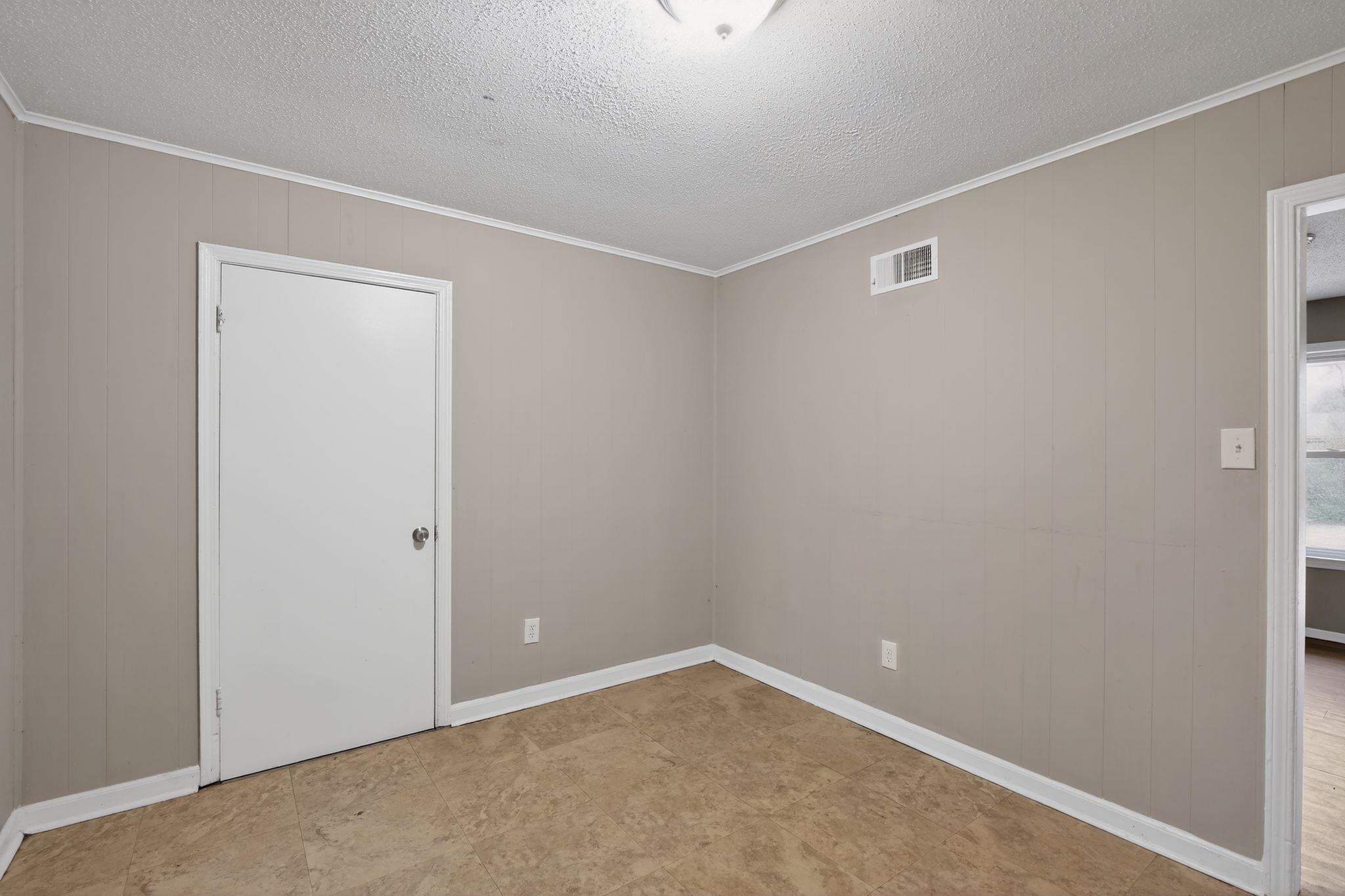4314 Ford Road Memphis, TN 38109 - Photo 5 of 31 Empty room with ornamental molding, a textured ceiling, and wooden walls