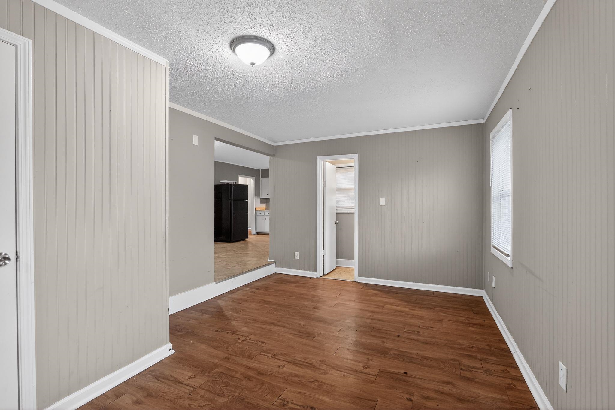 4314 Ford Road Memphis, TN 38109 - Photo 7 of 31 Empty room featuring dark wood finished floors, crown molding, wood walls, and a textured ceiling