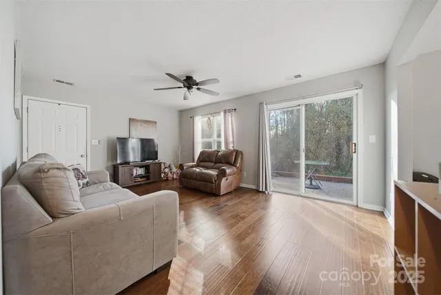a living room with furniture a ceiling fan and a flat screen tv