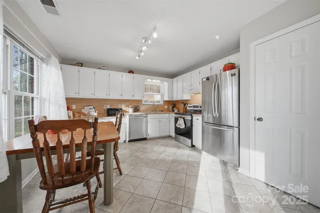 a kitchen with stainless steel appliances a refrigerator a stove a sink and chairs