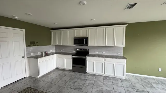 a kitchen with a sink a stove top oven and cabinets