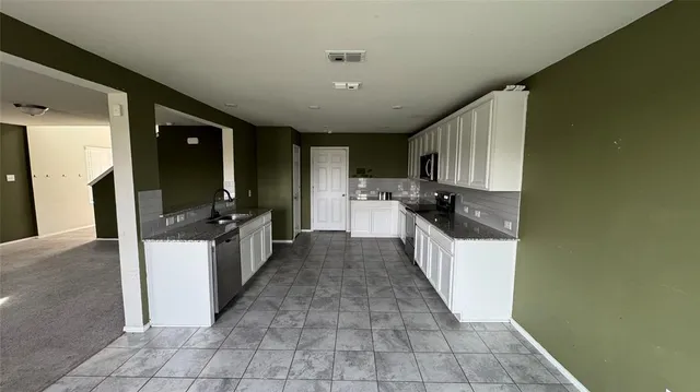 a large white kitchen with a large window and stainless steel appliances