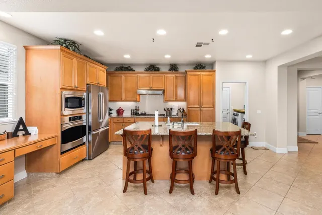 a large kitchen with lots of furniture a sink appliances and cabinets