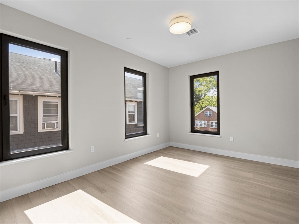249 Corey Road, Unit 309 Boston, MA 02135 - Photo 15 of 29 a view of an empty room with a window and wooden floor