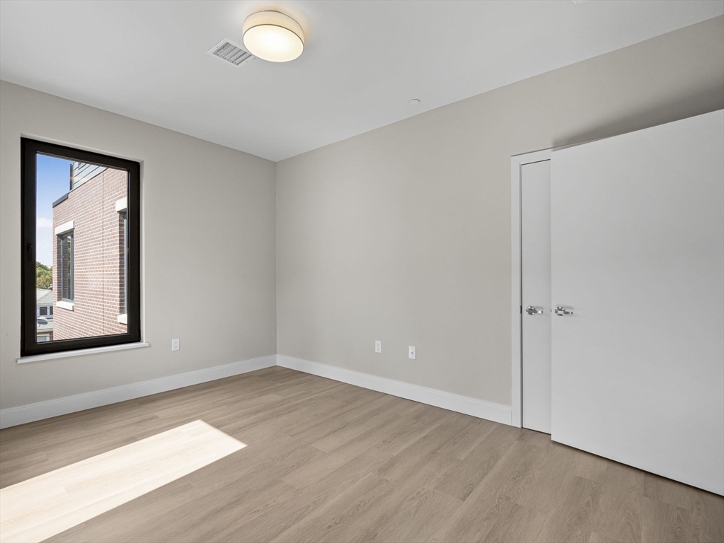 249 Corey Road, Unit 309 Boston, MA 02135 - Photo 16 of 29 a view of an empty room with wooden floor and a window