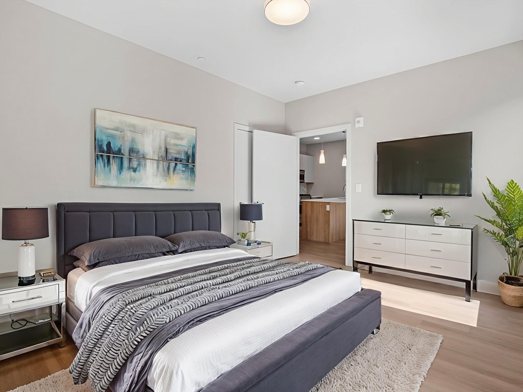 249 Corey Road, Unit 309 Boston, MA 02135 - Photo 2 of 29 a bedroom with a bed and a flat screen tv