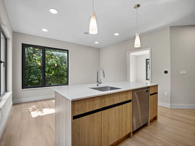a kitchen with a sink window and wooden floor