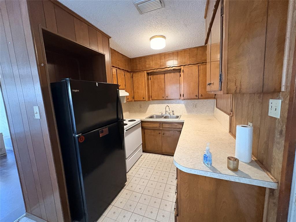 1829 South Center Street Denison, TX 75021 - Photo 13 of 29 a kitchen with a refrigerator a stove top oven a sink and dishwasher