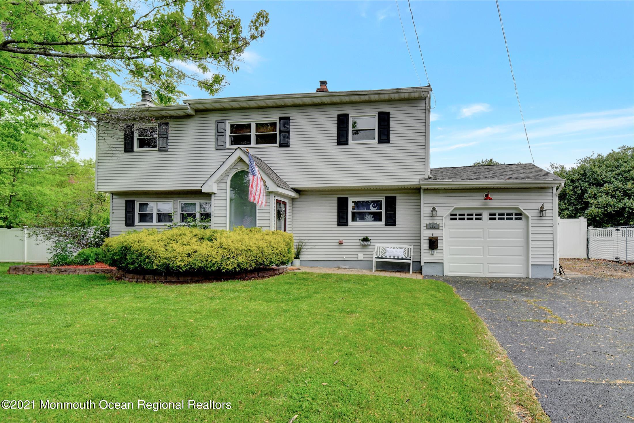 675 Harmony Road Middletown, NJ 07748 - Photo 2 of 25 a front view of a house with a yard and garage