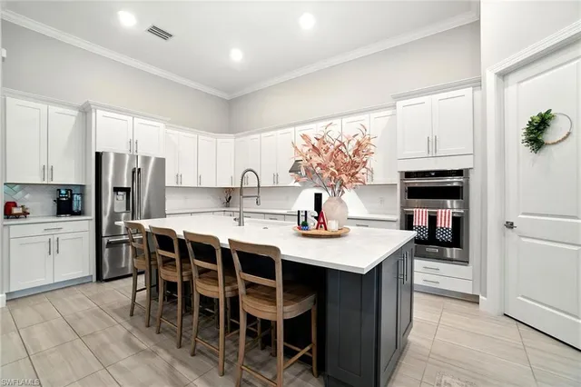 a kitchen with stainless steel appliances kitchen island granite countertop a table chairs and a refrigerator