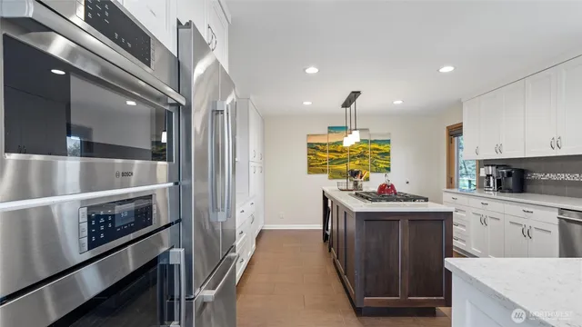 a kitchen with kitchen island granite countertop a sink a center island and stainless steel appliances