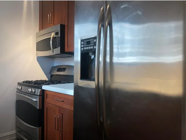 a kitchen with stainless steel appliances granite countertop a refrigerator a stove and a sink with wooden floor
