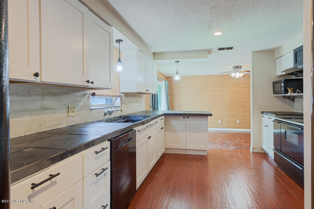 8759 Moss Haven Road Jacksonville, FL 32221 - Photo 11 of 29 a kitchen with granite countertop a sink cabinets stainless steel appliances and wooden floor