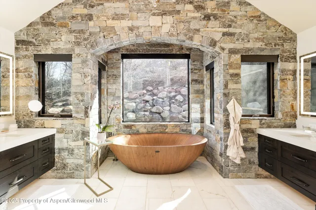 a spacious bathroom with a tub a double vanity sink a mirror and shower